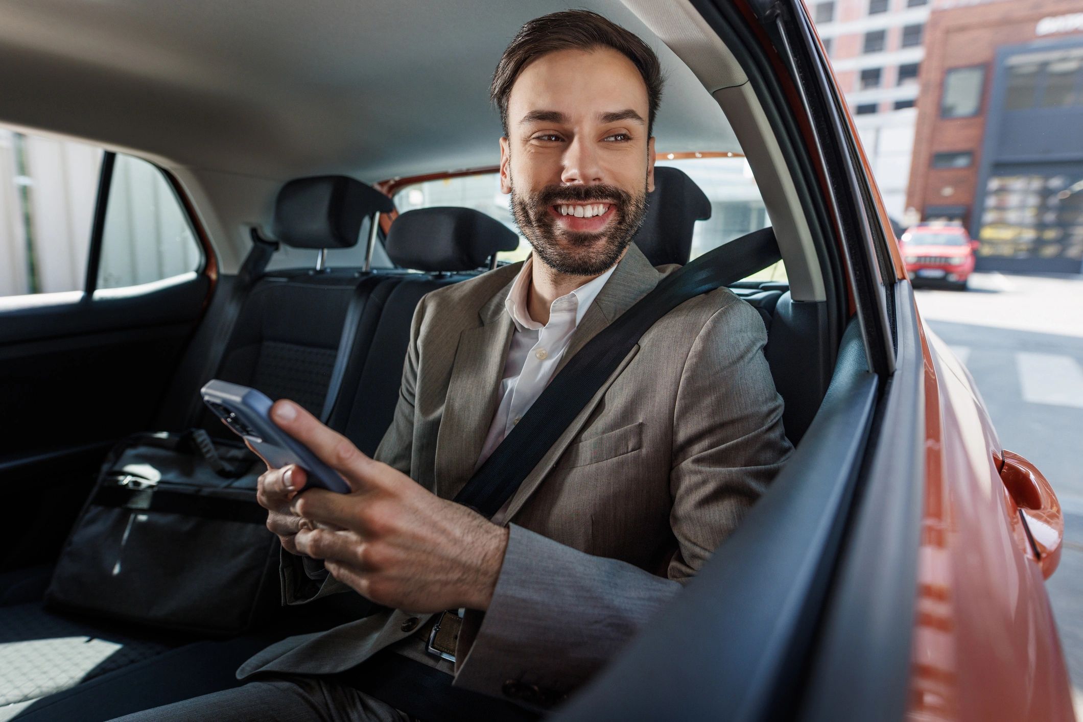 Passenger using smartphone in the backseat of a car